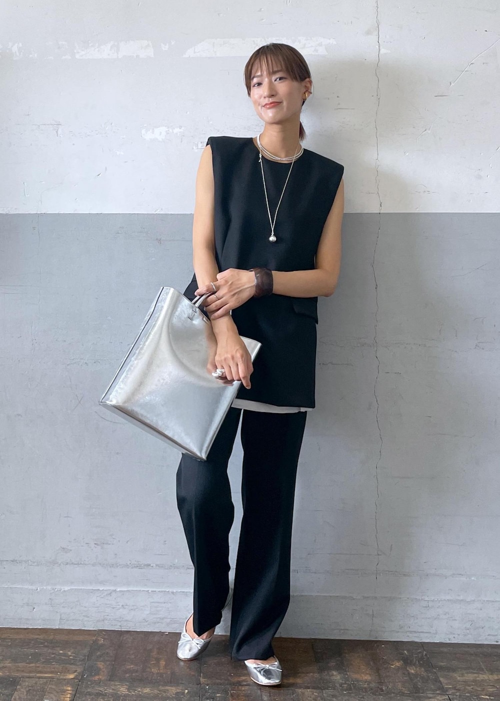 シルバー系のバレエシューズ、シルバー系のトートバッグ、ブラック系のベストを着用したレディースの夏コーディネートの2枚目の写真