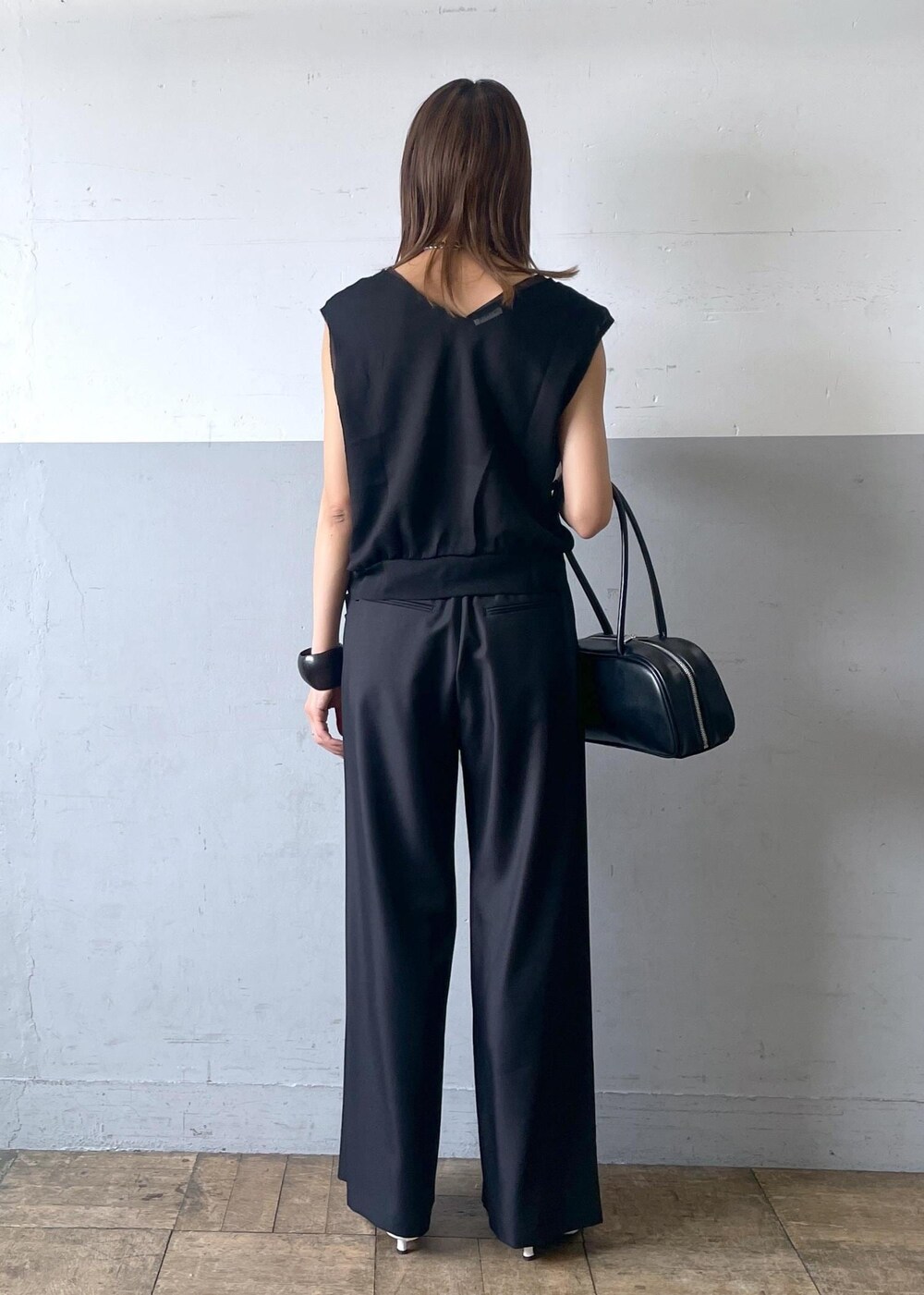 ブラック系のボストンバッグ、ホワイト系のパンプス、ブラック系のスラックスを着用したレディースの夏コーディネートの3枚目の写真