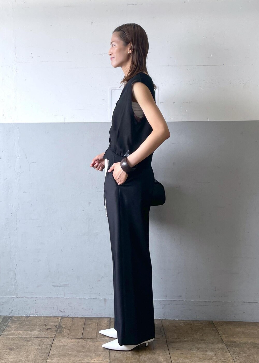 ブラック系のボストンバッグ、ホワイト系のパンプス、ブラック系のスラックスを着用したレディースの夏コーディネートの2枚目の写真