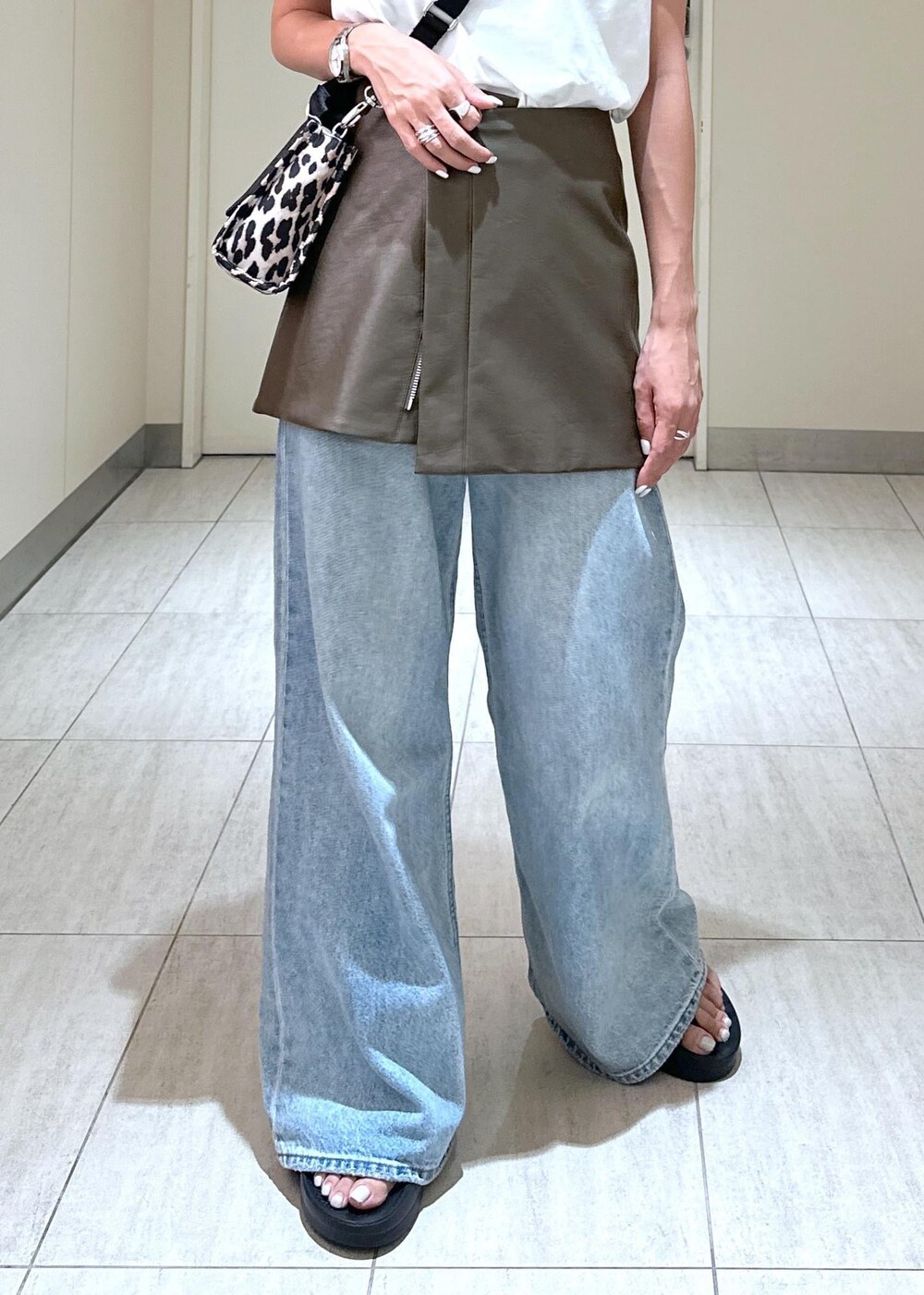 ベージュ系のトートバッグ、ブラウン系のスカート、ホワイト系のTシャツ/カットソーを着用したレディースの夏コーディネートの7枚目の写真