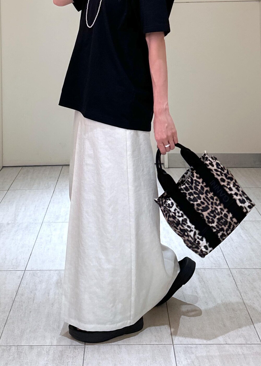 ブラウン系のショルダーバッグ、ホワイト系のスカート、ブラック系のTシャツ/カットソーを着用したレディースの夏コーディネートの8枚目の写真
