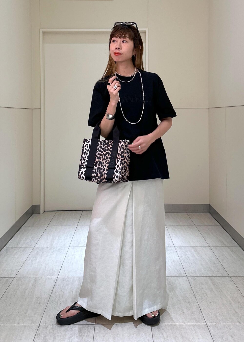 ブラウン系のショルダーバッグ、ホワイト系のスカート、ブラック系のTシャツ/カットソーを着用したレディースの夏コーディネートの4枚目の写真