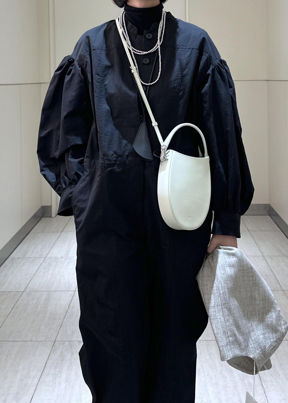 ホワイト系のハンドバッグ、ベージュ系のベスト、ブラック系のつなぎ/オールインワンを着用したレディースの冬コーディネートの5枚目の写真