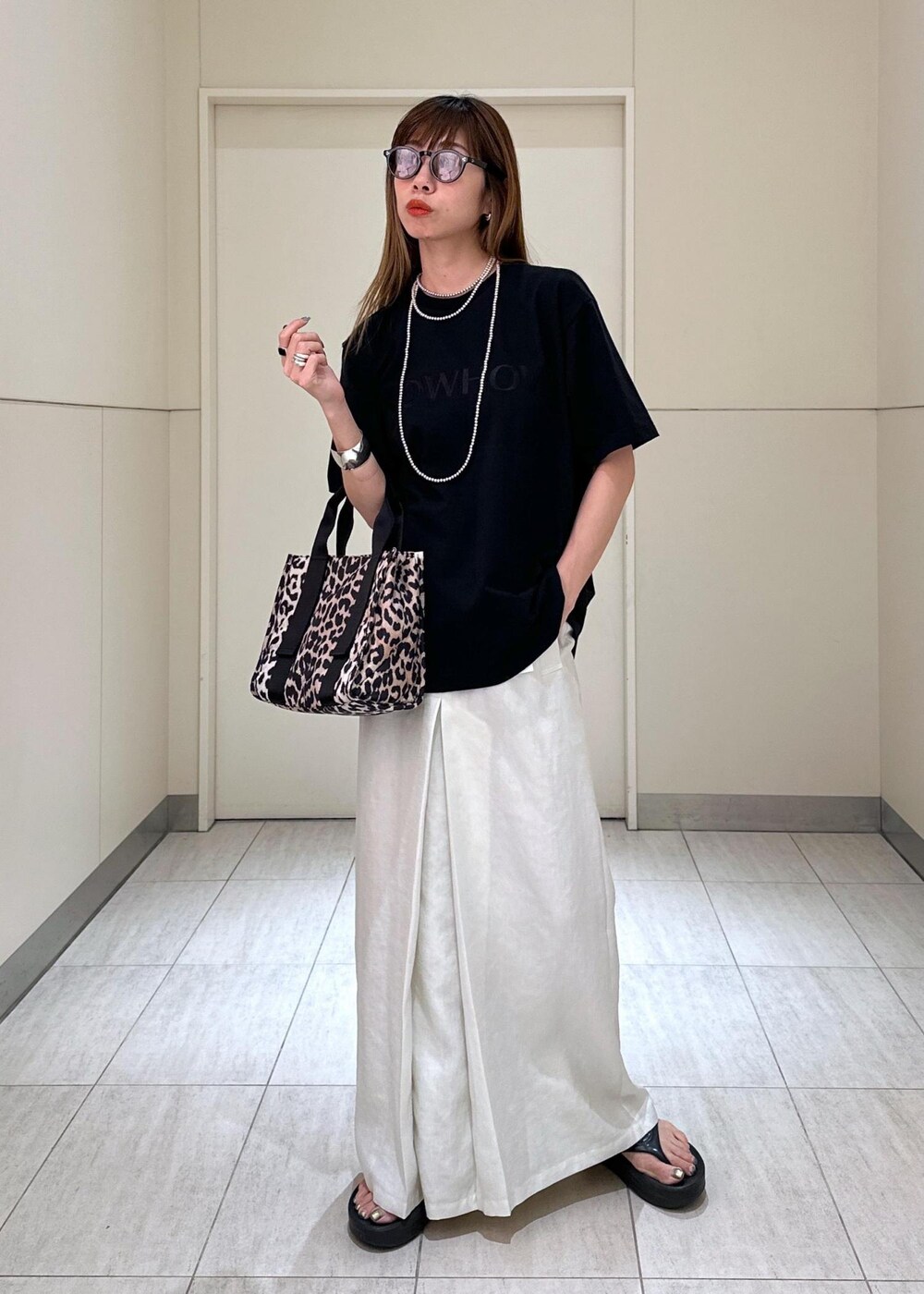 ブラウン系のショルダーバッグ、ホワイト系のスカート、ブラック系のTシャツ/カットソーを着用したレディースの夏コーディネートの2枚目の写真