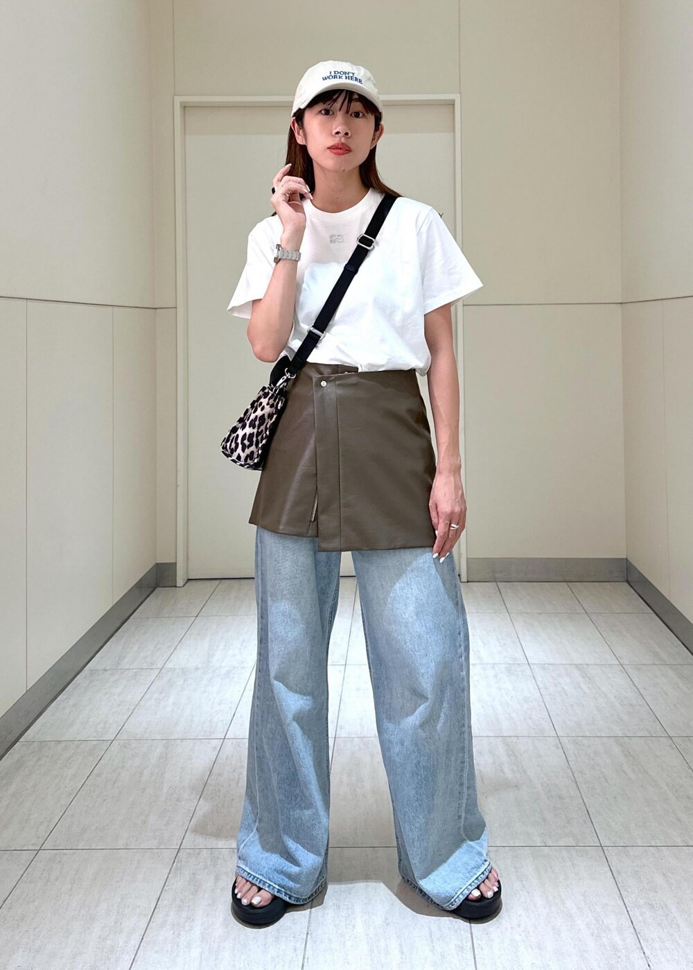 ベージュ系のトートバッグ、ブラウン系のスカート、ホワイト系のTシャツ/カットソーを着用したレディースの夏コーディネートの2枚目の写真