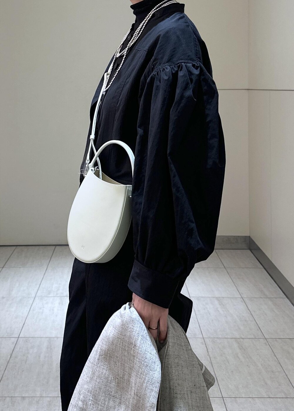 ホワイト系のハンドバッグ、ベージュ系のベスト、ブラック系のつなぎ/オールインワンを着用したレディースの冬コーディネートの6枚目の写真