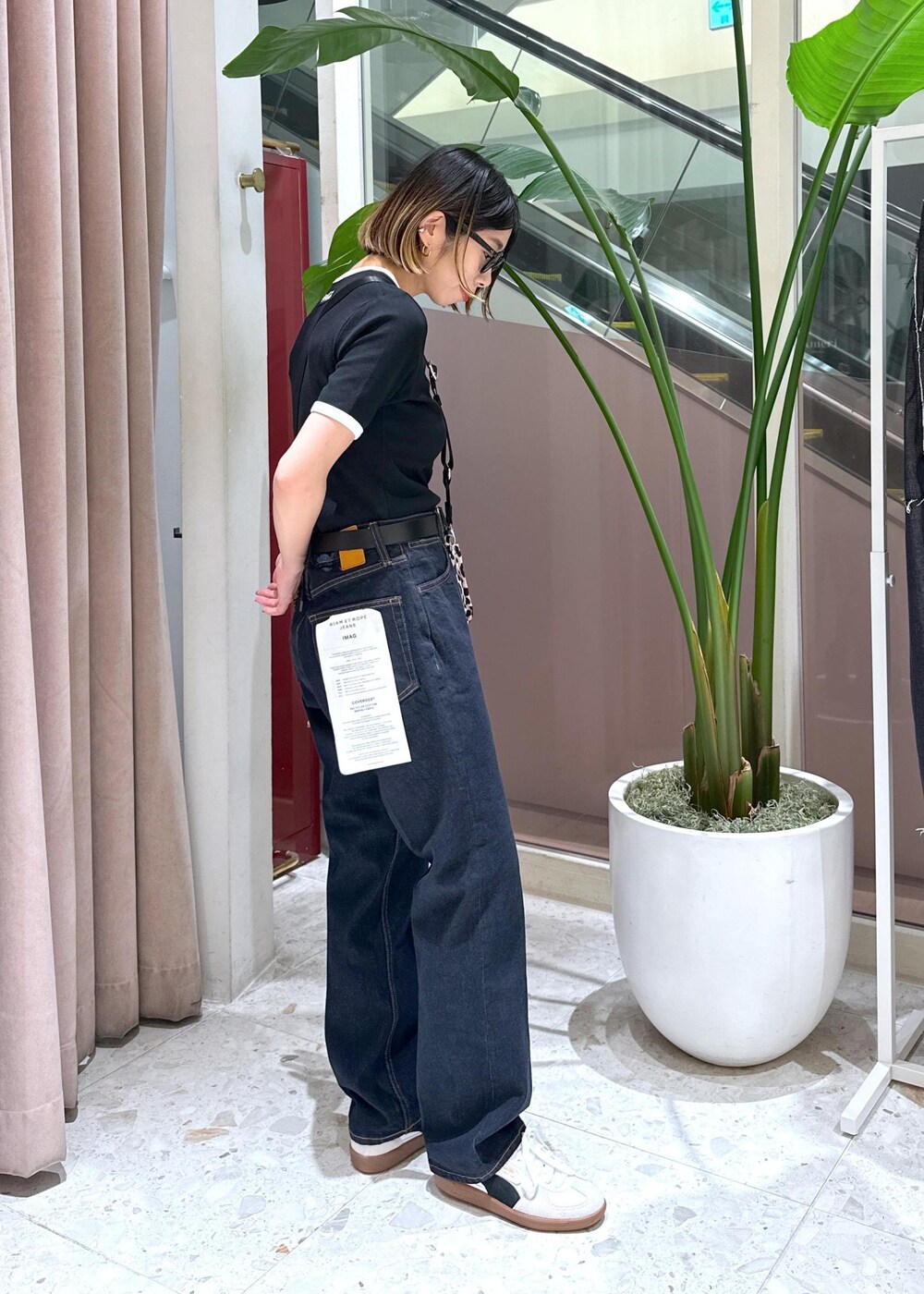 ブルー系のデニムパンツ、ベージュ系のショルダーバッグ、ホワイト系のスニーカーを着用したレディースの夏コーディネートの2枚目の写真