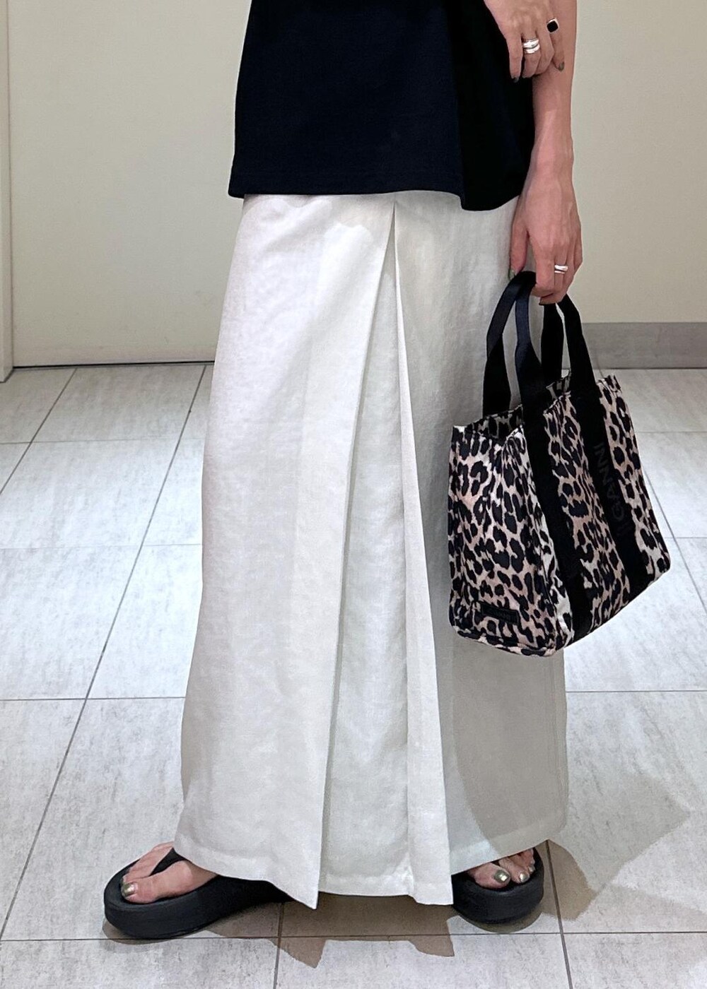 ブラウン系のショルダーバッグ、ホワイト系のスカート、ブラック系のTシャツ/カットソーを着用したレディースの夏コーディネートの7枚目の写真