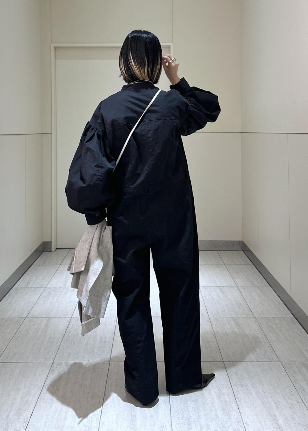 ホワイト系のハンドバッグ、ベージュ系のベスト、ブラック系のつなぎ/オールインワンを着用したレディースの冬コーディネートの4枚目の写真