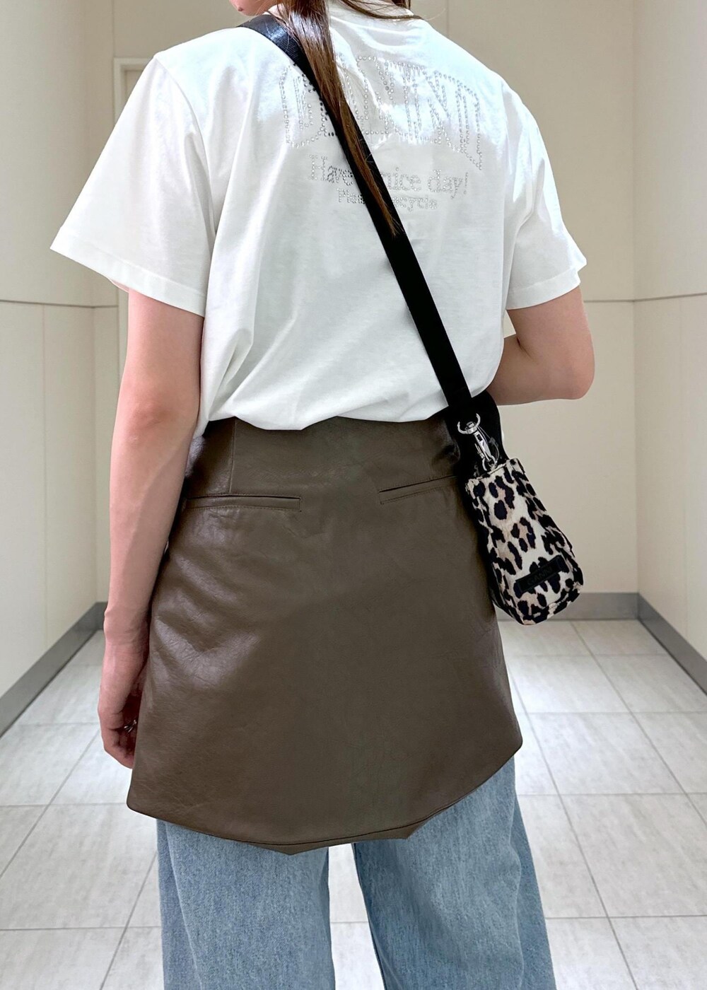 ベージュ系のトートバッグ、ブラウン系のスカート、ホワイト系のTシャツ/カットソーを着用したレディースの夏コーディネートの6枚目の写真