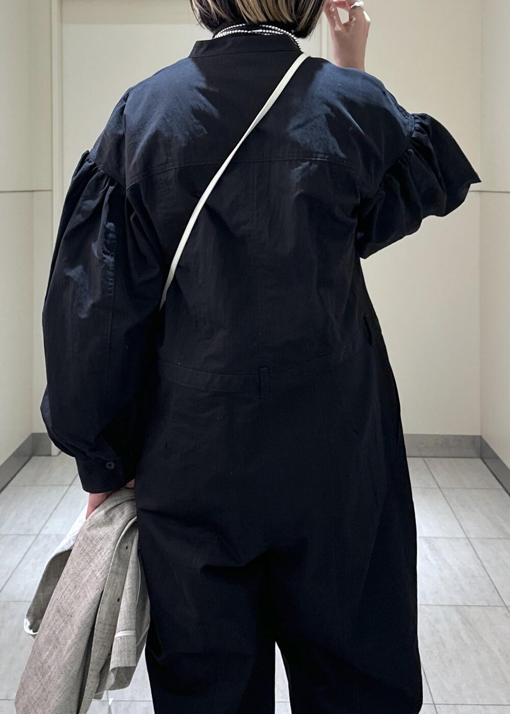 ホワイト系のハンドバッグ、ベージュ系のベスト、ブラック系のつなぎ/オールインワンを着用したレディースの冬コーディネートの7枚目の写真