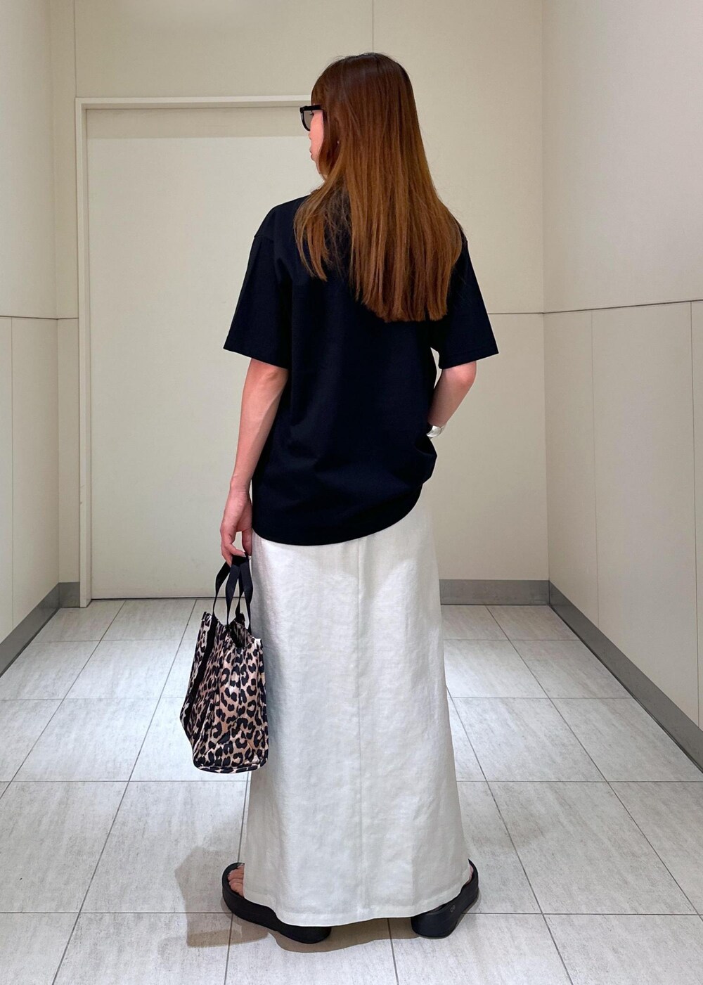 ブラウン系のショルダーバッグ、ホワイト系のスカート、ブラック系のTシャツ/カットソーを着用したレディースの夏コーディネートの3枚目の写真