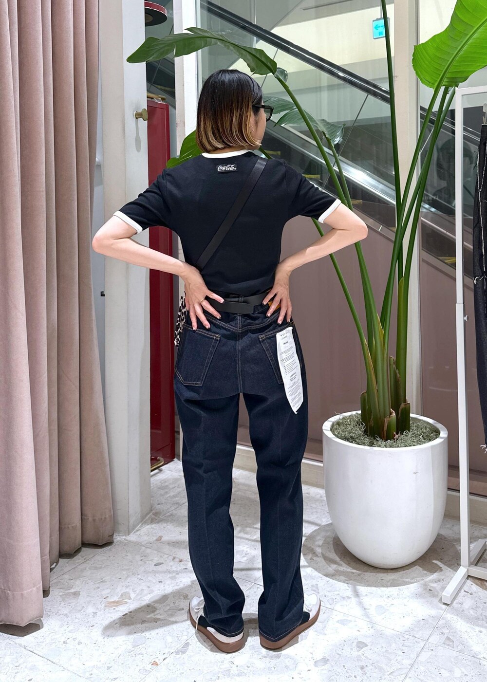 ブルー系のデニムパンツ、ベージュ系のショルダーバッグ、ホワイト系のスニーカーを着用したレディースの夏コーディネートの3枚目の写真