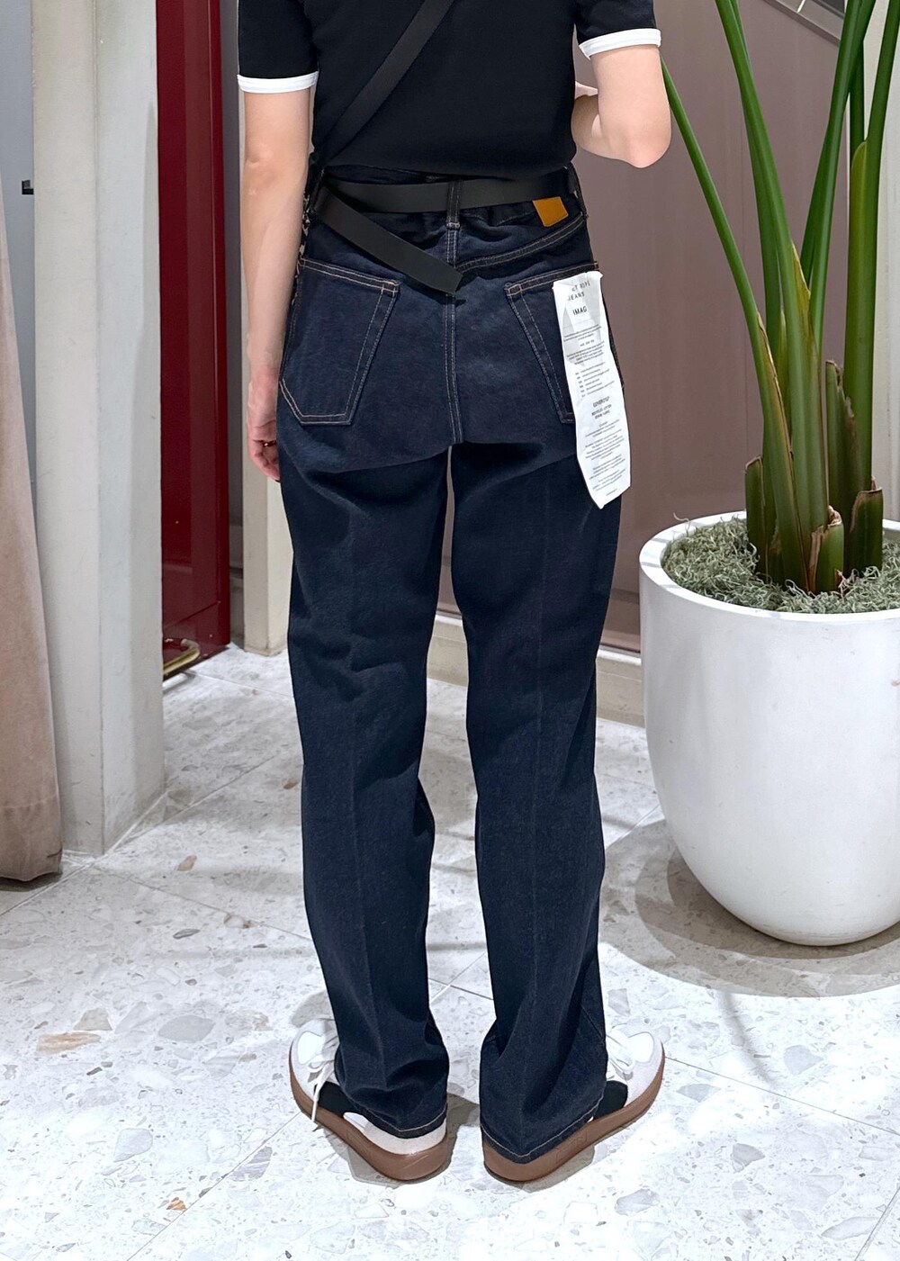 ブルー系のデニムパンツ、ベージュ系のショルダーバッグ、ホワイト系のスニーカーを着用したレディースの夏コーディネートの9枚目の写真
