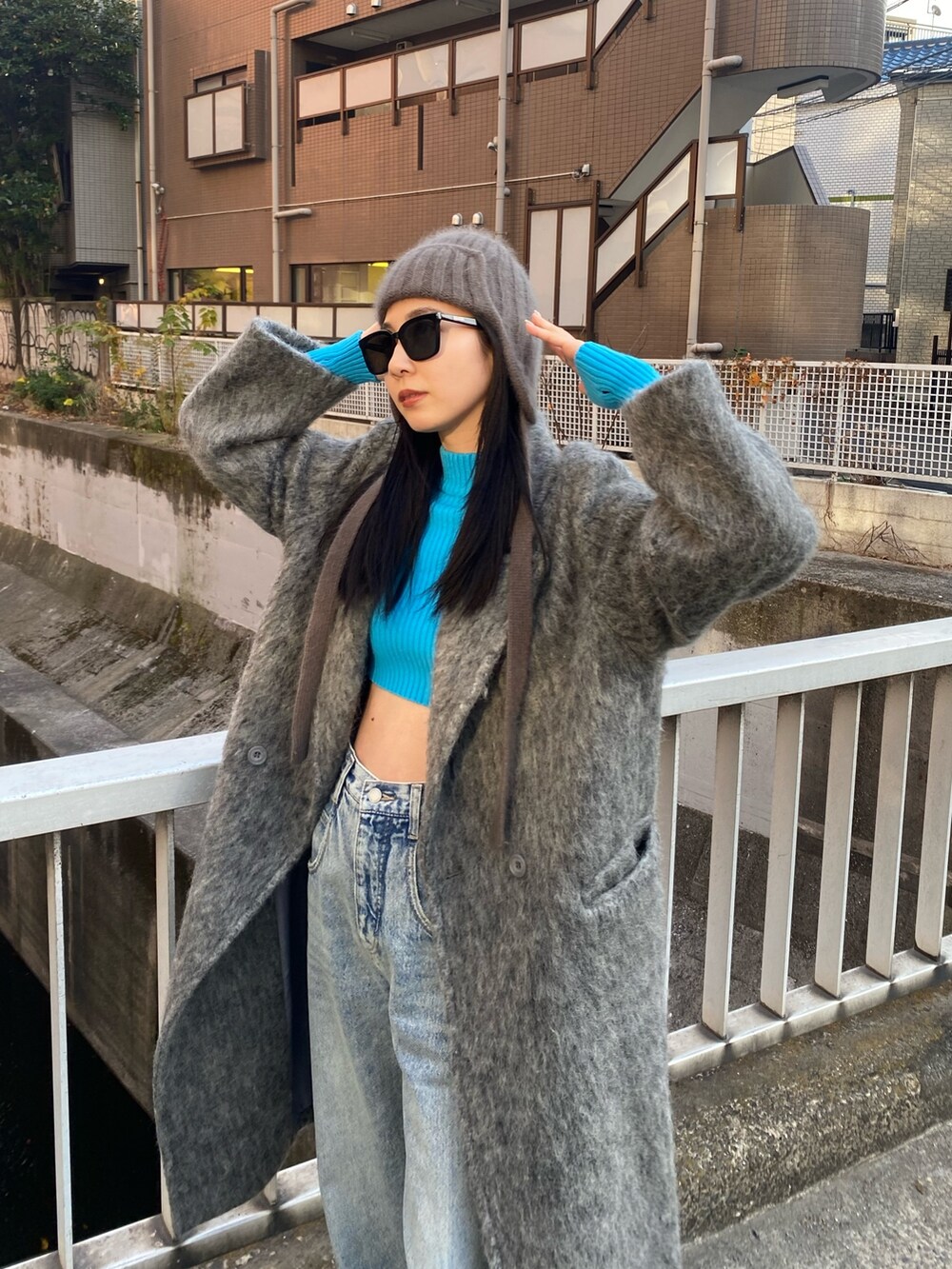 グレー系のチェスターコート、ブルー系のデニムパンツ、ブルー系のニット/セーターを着用したレディースの冬コーディネートの3枚目の写真