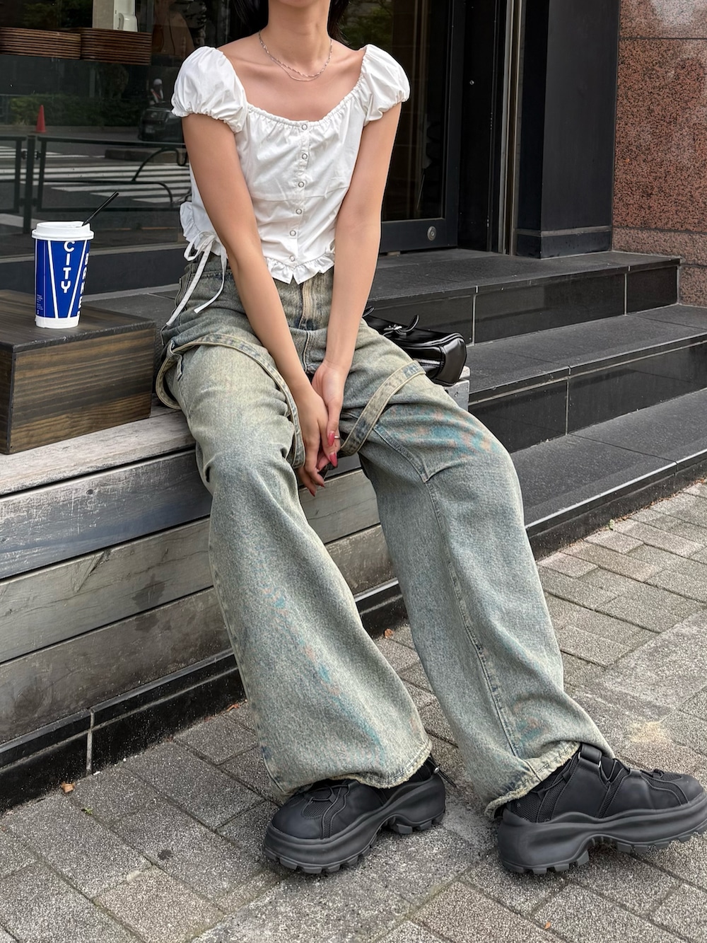 ブルー系のデニムパンツ、ブラック系のサンダル、ホワイト系のTシャツ/カットソーを着用したレディースの春コーディネートの3枚目の写真