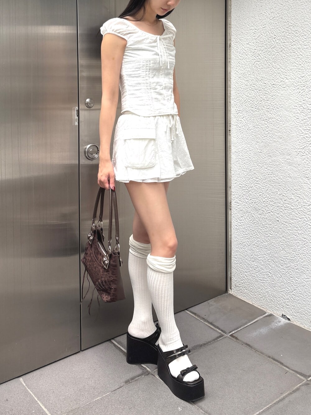 ブラック系のサンダル、ホワイト系のシャツ/ブラウス、ホワイト系のスカートを着用したレディースの夏コーディネートの2枚目の写真