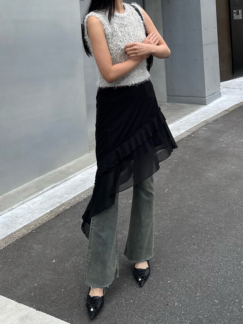 ブラック系のスカート、ブルー系のデニムパンツ、ブラック系のパンプスを着用したレディースの春コーディネートの2枚目の写真