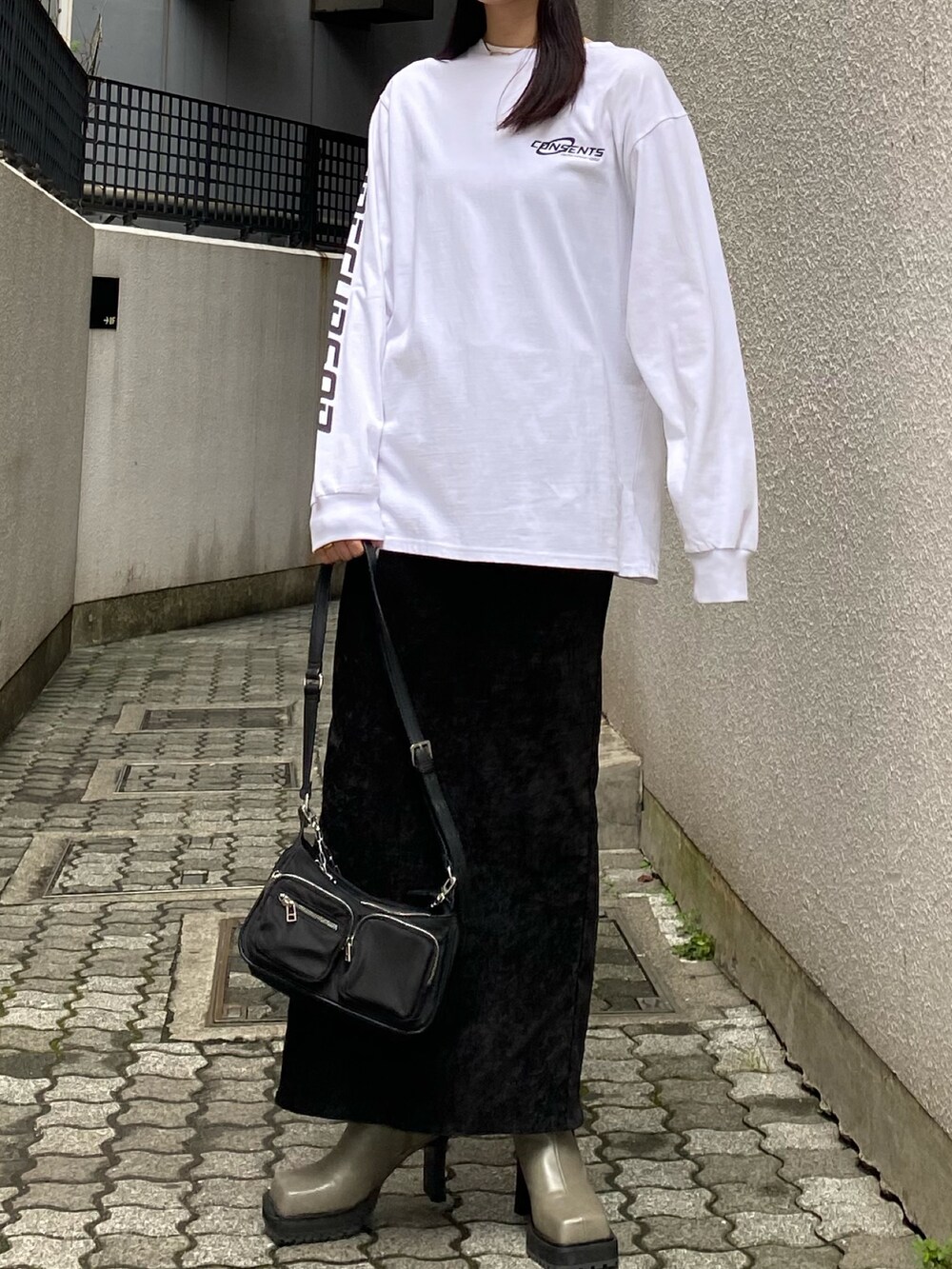 ホワイト系のTシャツ/カットソー、ブラック系のスカート、グレー系のブーツを着用したレディースの秋コーディネートの3枚目の写真