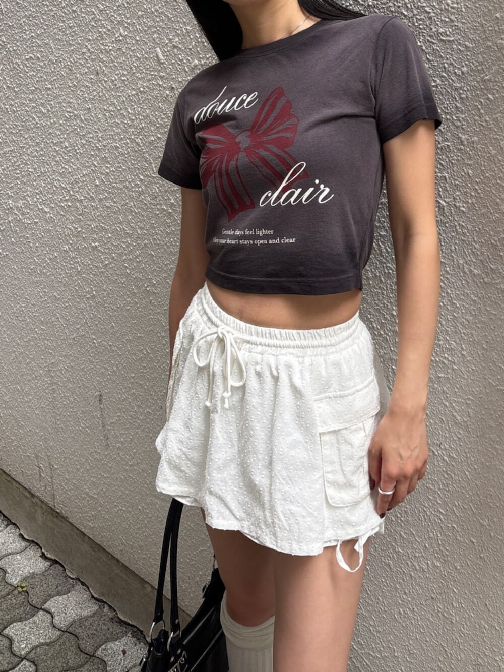 ブラック系のショルダーバッグ、ブラック系のサンダル、ブラック系のTシャツ/カットソーを着用したレディースの夏コーディネートの4枚目の写真