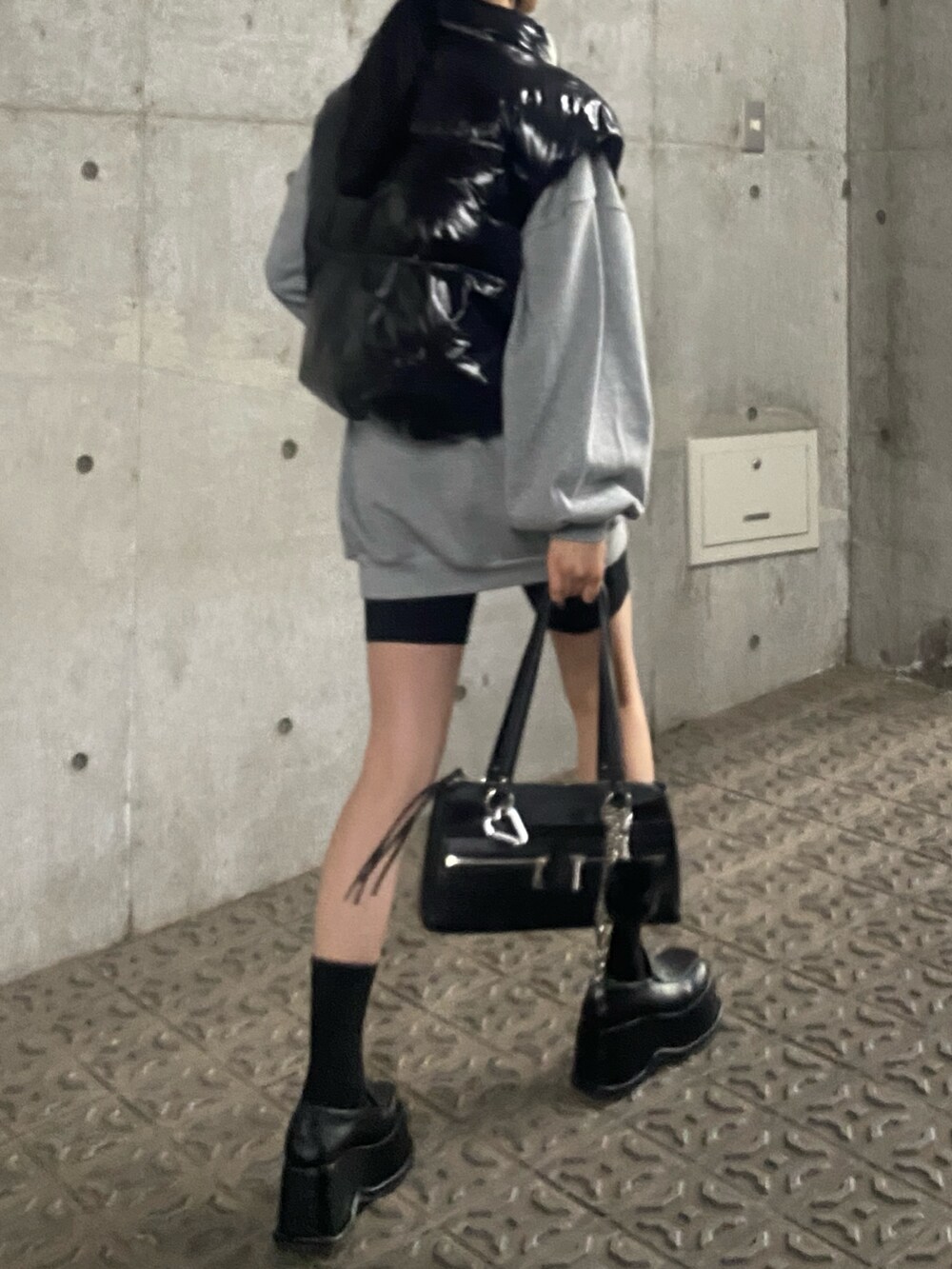 グレー系のスウェット、ブラック系のダウンベスト、ブラック系のローファーを着用したレディースの秋コーディネートの2枚目の写真