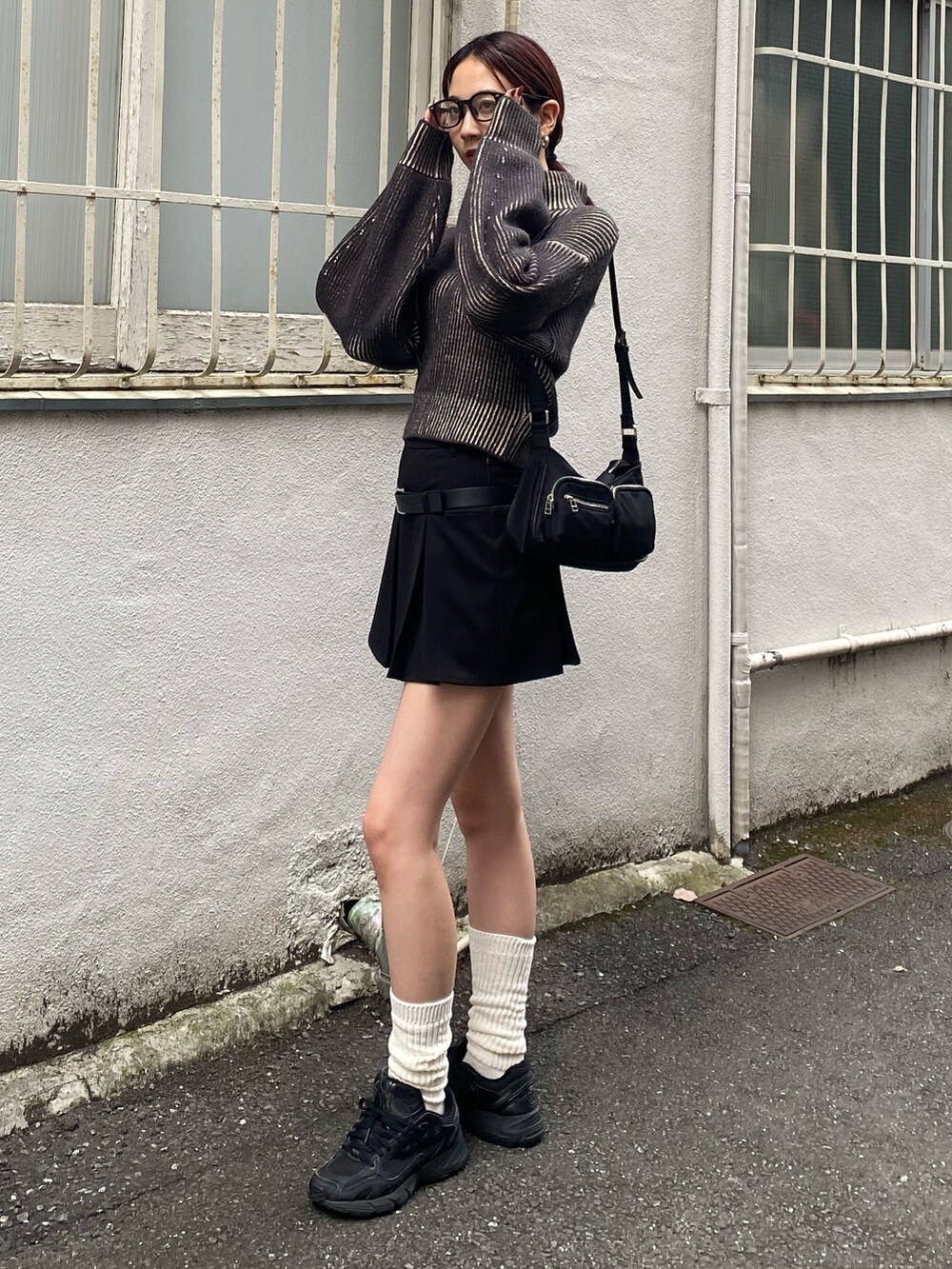 ブラック系のハンドバッグ、ブラック系のニット/セーター、ブラック系のスカートを着用したレディースの秋コーディネートの2枚目の写真