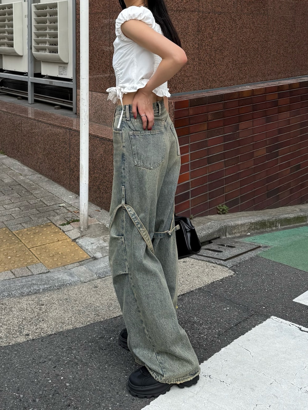 ブルー系のデニムパンツ、ブラック系のサンダル、ホワイト系のTシャツ/カットソーを着用したレディースの春コーディネートの2枚目の写真