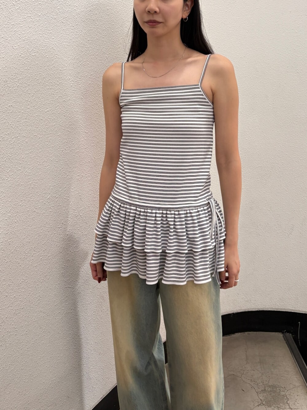 ブルー系のデニムパンツ、ブラック系のサンダル、ブラック系のハンドバッグを着用したレディースの夏コーディネートの5枚目の写真