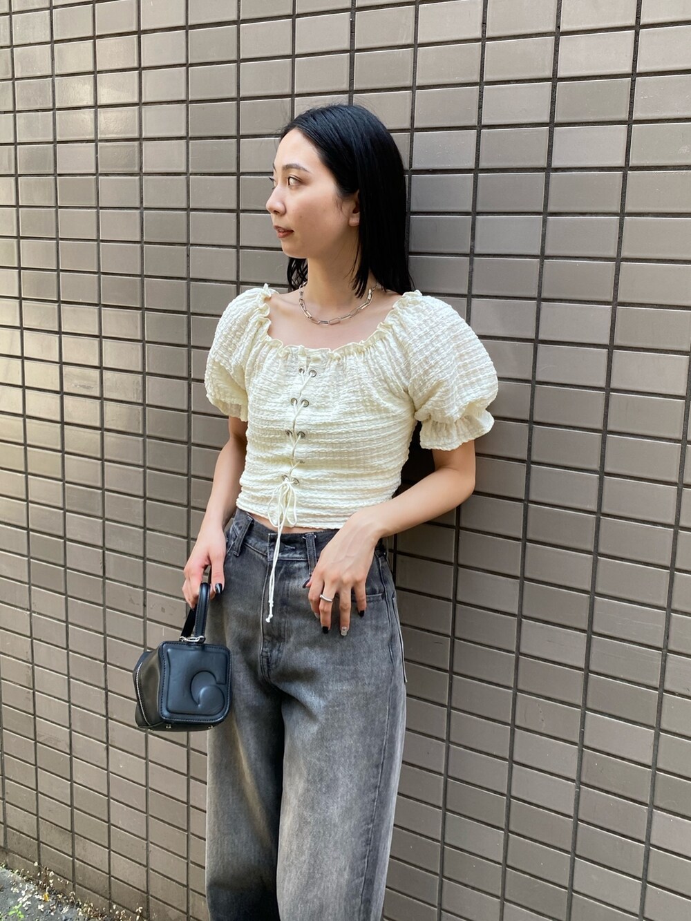 グレー系のデニムパンツ、ホワイト系のTシャツ/カットソー、ブラック系のハンドバッグを着用したレディースの夏コーディネートの3枚目の写真