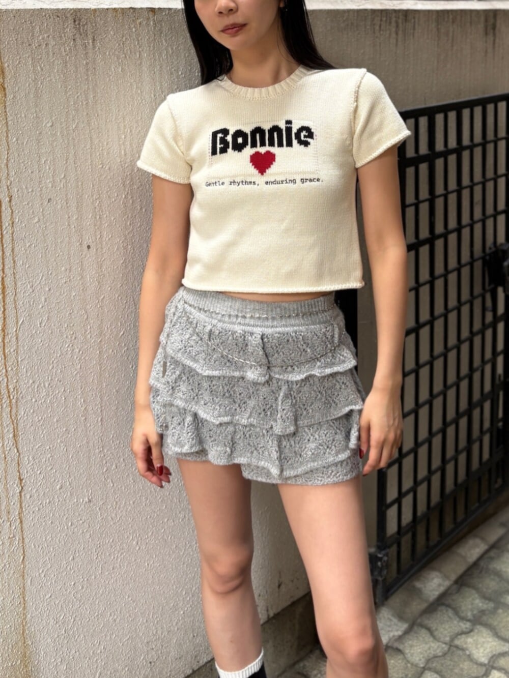 ブラック系のブーツ、ホワイト系のニット/セーター、グレー系のスカートを着用したレディースの夏コーディネートの4枚目の写真