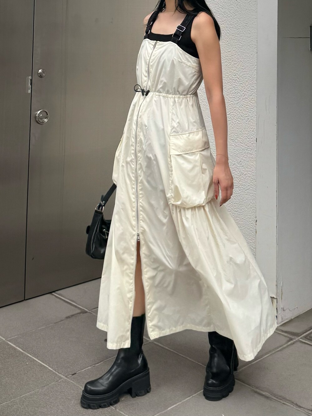 ホワイト系のワンピース、ブラック系のブーツを着用したレディースの夏コーディネートの2枚目の写真