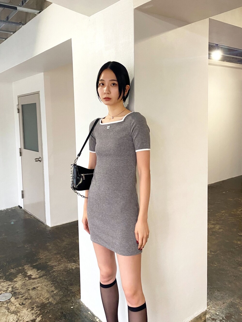 グレー系のワンピース、ブラック系のサンダル、ブラック系のショルダーバッグを着用したレディースの夏コーディネートの2枚目の写真