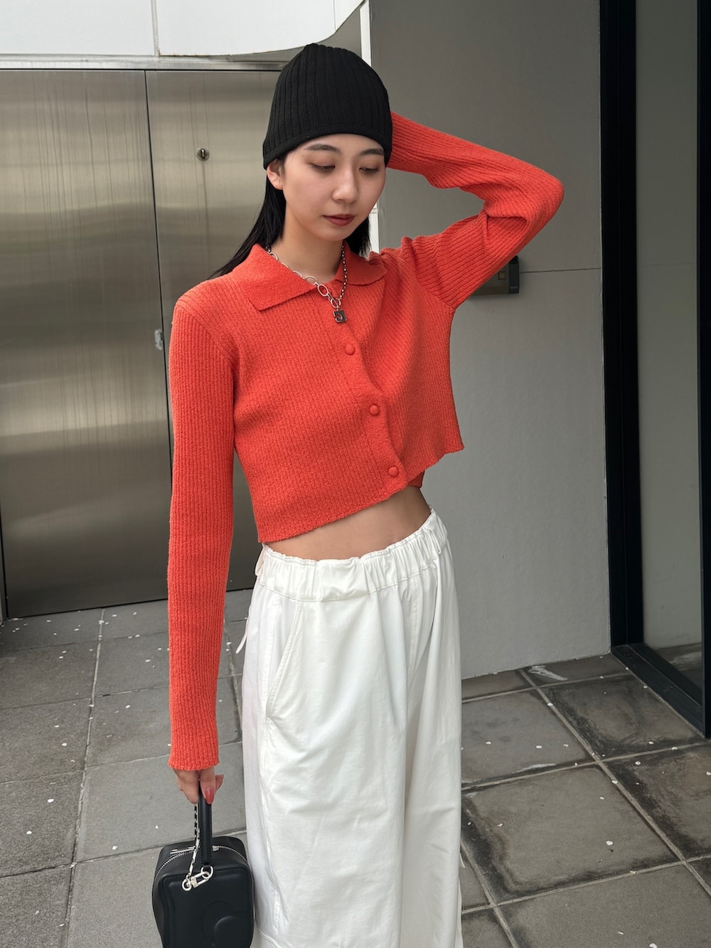 オレンジ系のニット/セーター、ホワイト系のカーゴパンツを着用したレディースの春コーディネートの3枚目の写真