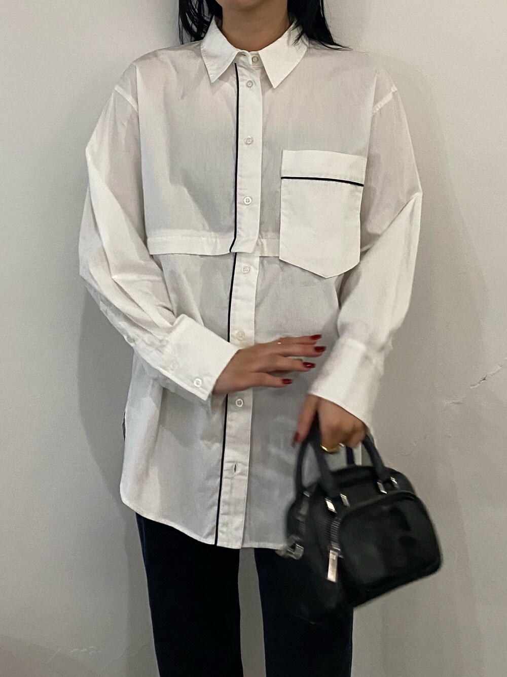 ブラック系のパンプス、ブラック系のハンドバッグ、ブルー系のデニムパンツを着用したレディースの春コーディネートの2枚目の写真