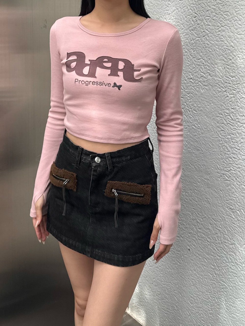 ピンク系のTシャツ/カットソー、ブラック系のスカート、ブラック系のブーツを着用したレディースの秋コーディネートの2枚目の写真