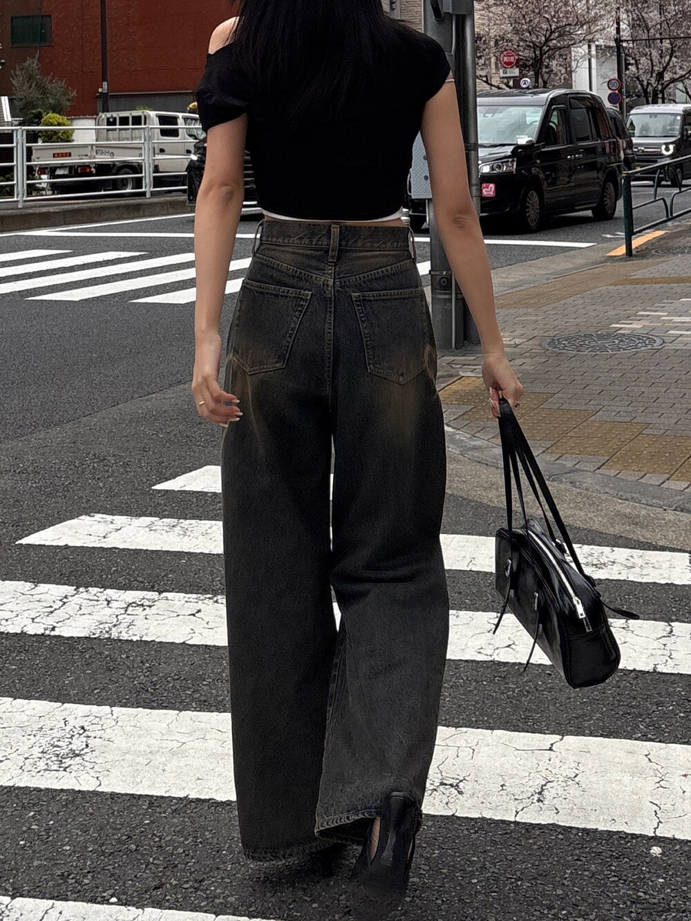 ブルー系のデニムパンツ、ブラック系のパンプス、ブラック系のハンドバッグを着用したレディースの夏コーディネートの2枚目の写真