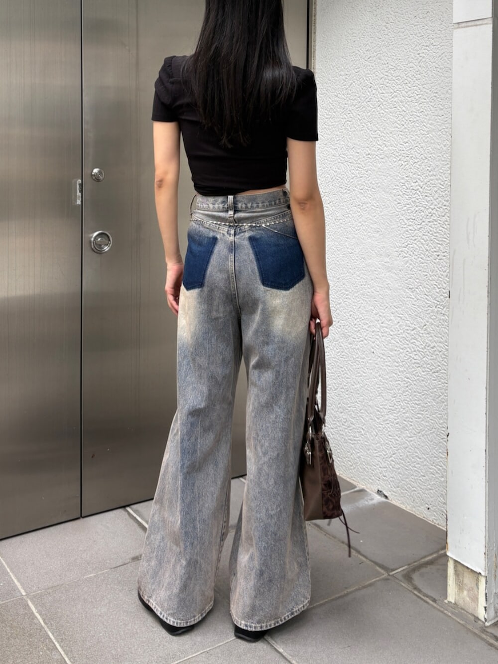 ブラック系のサンダル、ブルー系のデニムパンツ、ブラウン系のショルダーバッグを着用したレディースの夏コーディネートの3枚目の写真