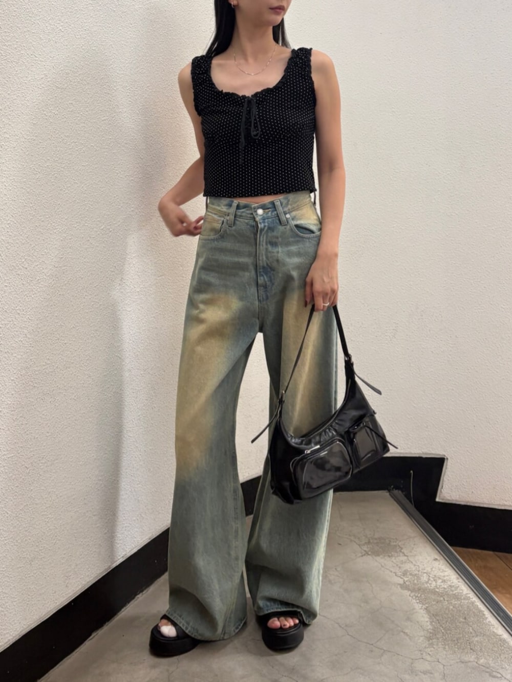 ブルー系のデニムパンツ、ブラック系のハンドバッグ、ブラック系のサンダルを着用したレディースの夏コーディネートの5枚目の写真