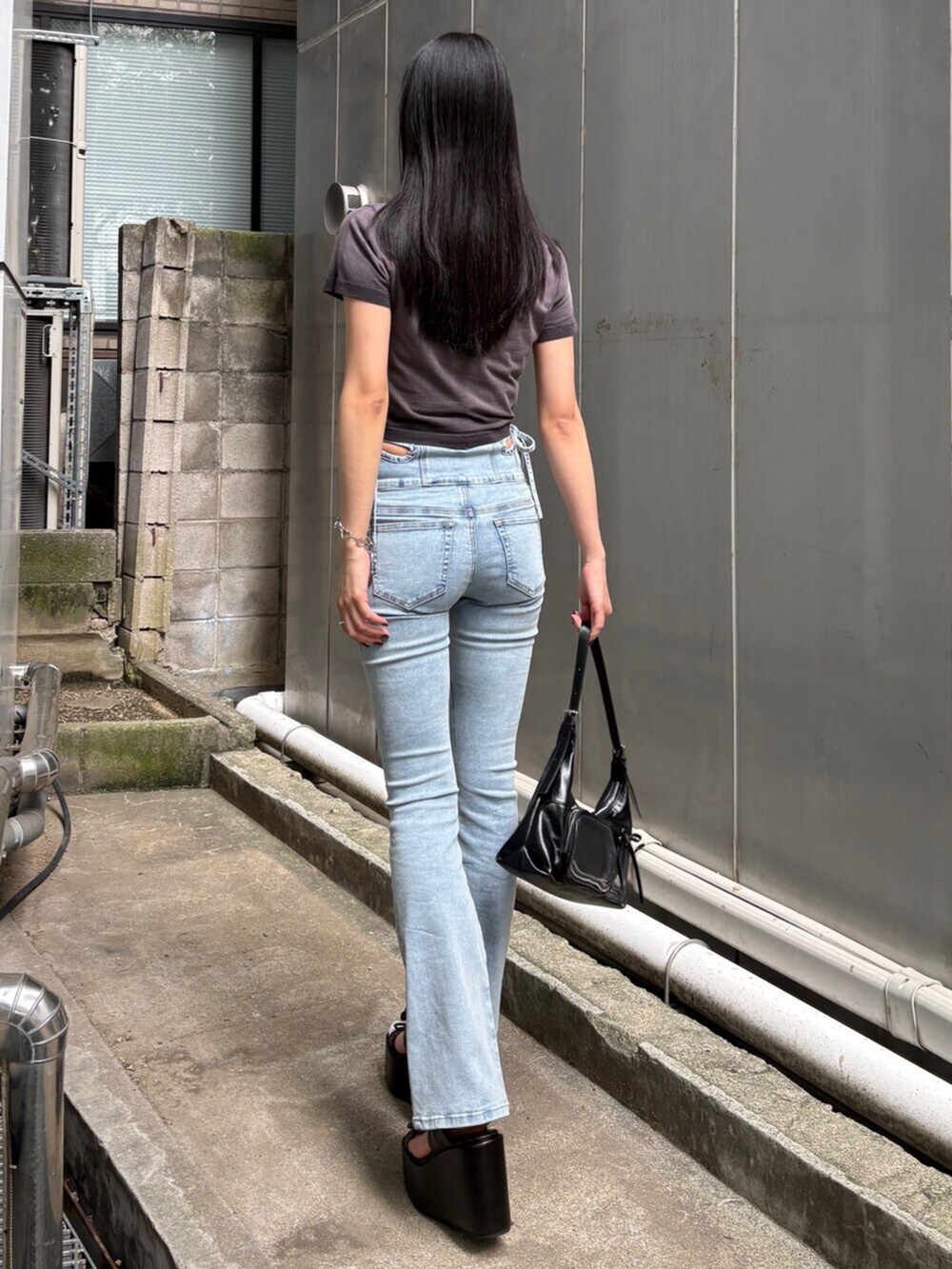 ブラック系のサンダル、ブラック系のTシャツ/カットソー、ブルー系のデニムパンツを着用したレディースの夏コーディネートの3枚目の写真