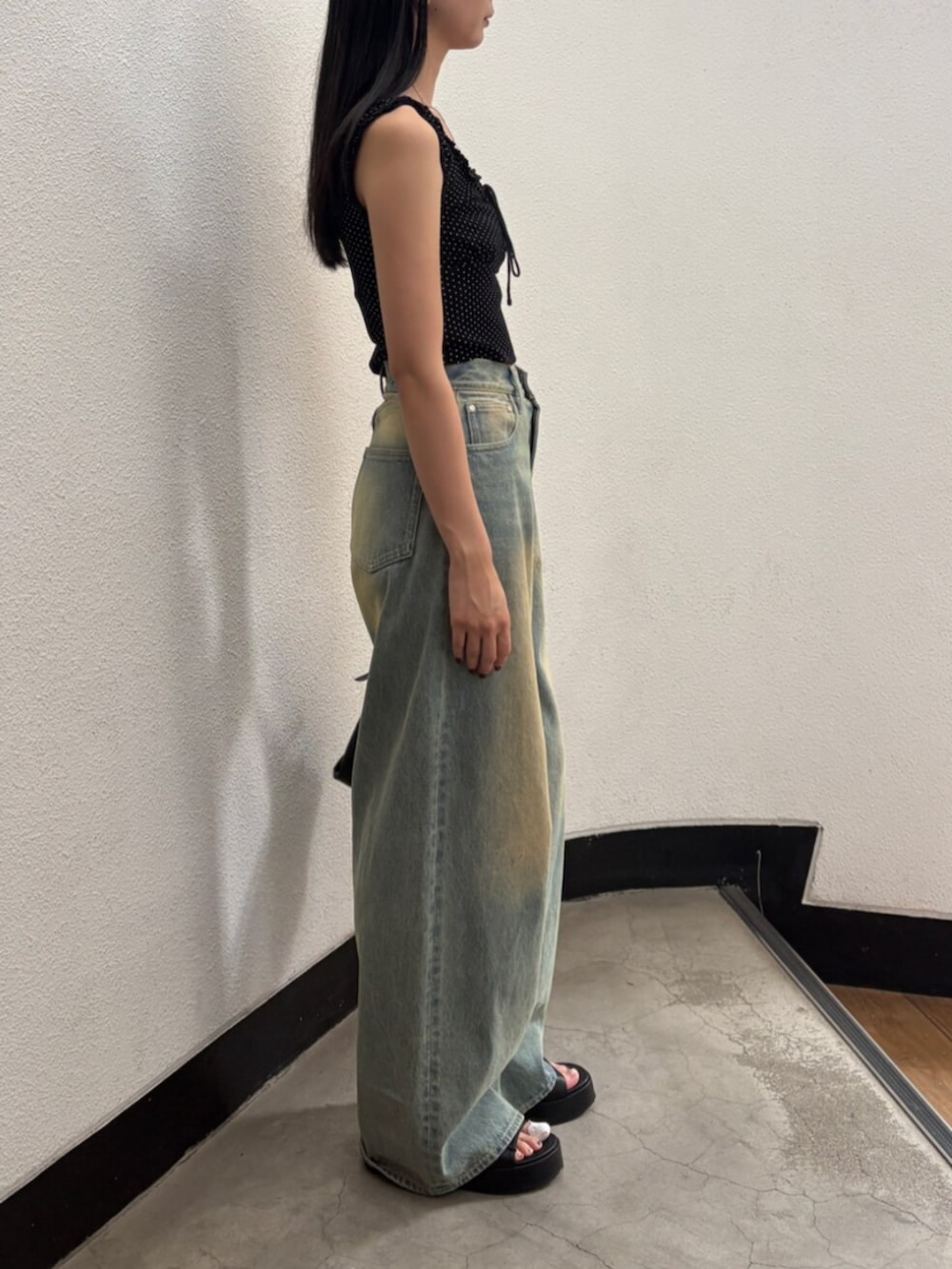 ブルー系のデニムパンツ、ブラック系のハンドバッグ、ブラック系のサンダルを着用したレディースの夏コーディネートの4枚目の写真