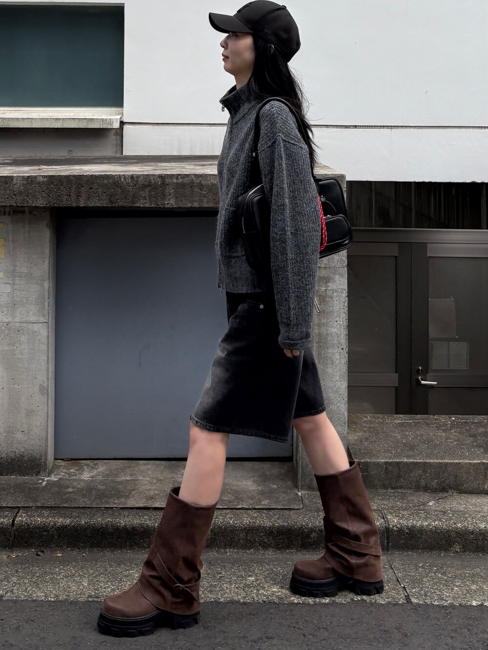 グレー系のカーディガン/ボレロ、ブラック系のハンドバッグ、ブラック系のデニムパンツを着用したレディースの冬コーディネートの2枚目の写真