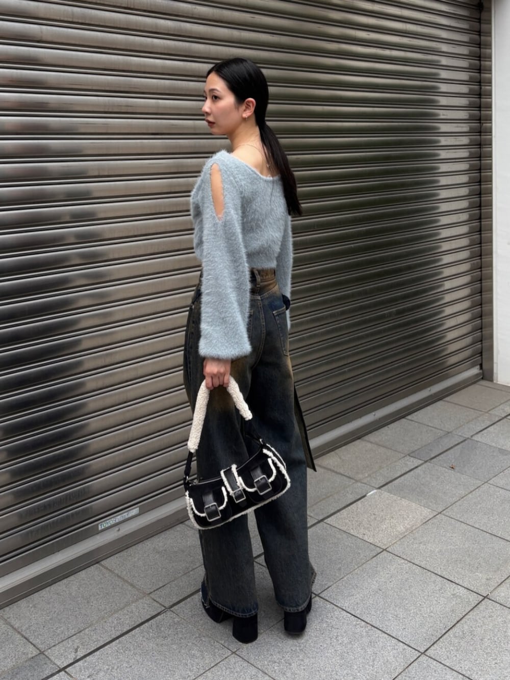 ブルー系のニット/セーター、ブルー系のデニムパンツ、ブラック系のハンドバッグを着用したレディースの秋コーディネートの4枚目の写真