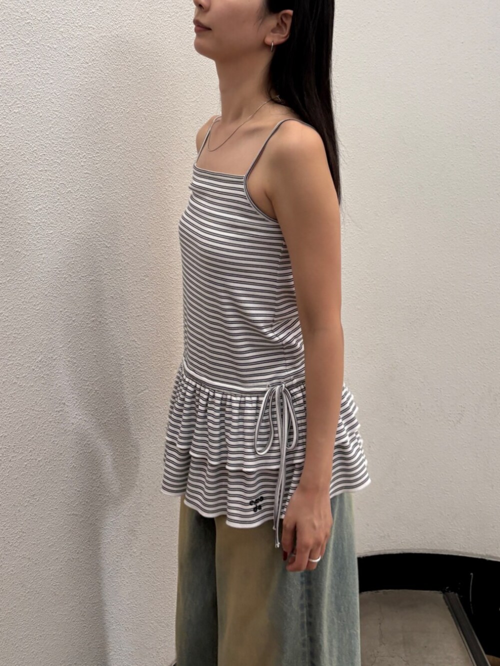 ブルー系のデニムパンツ、ブラック系のサンダル、ブラック系のハンドバッグを着用したレディースの夏コーディネートの6枚目の写真