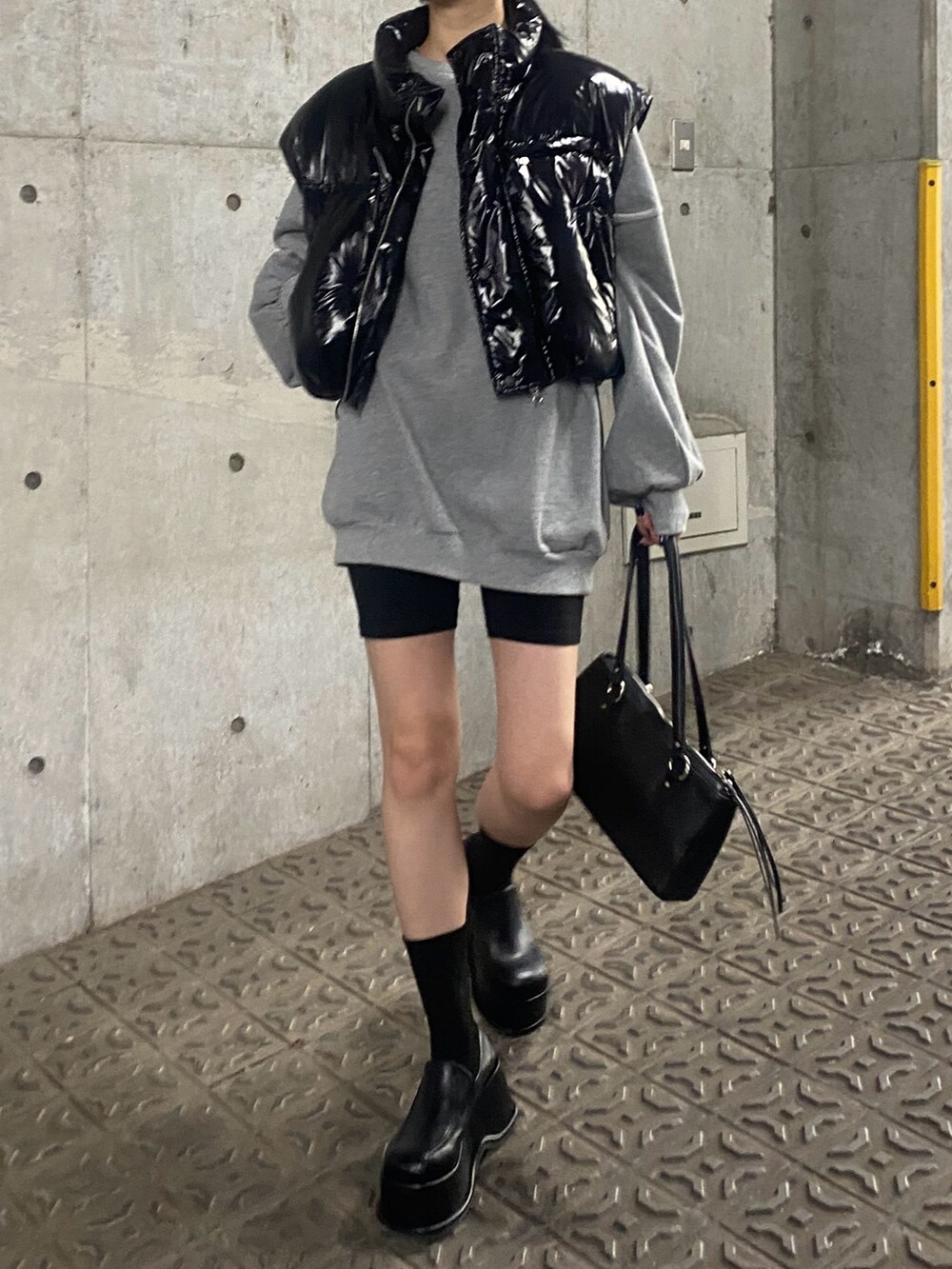 グレー系のスウェット、ブラック系のダウンベスト、ブラック系のローファーを着用したレディースの秋コーディネートの3枚目の写真