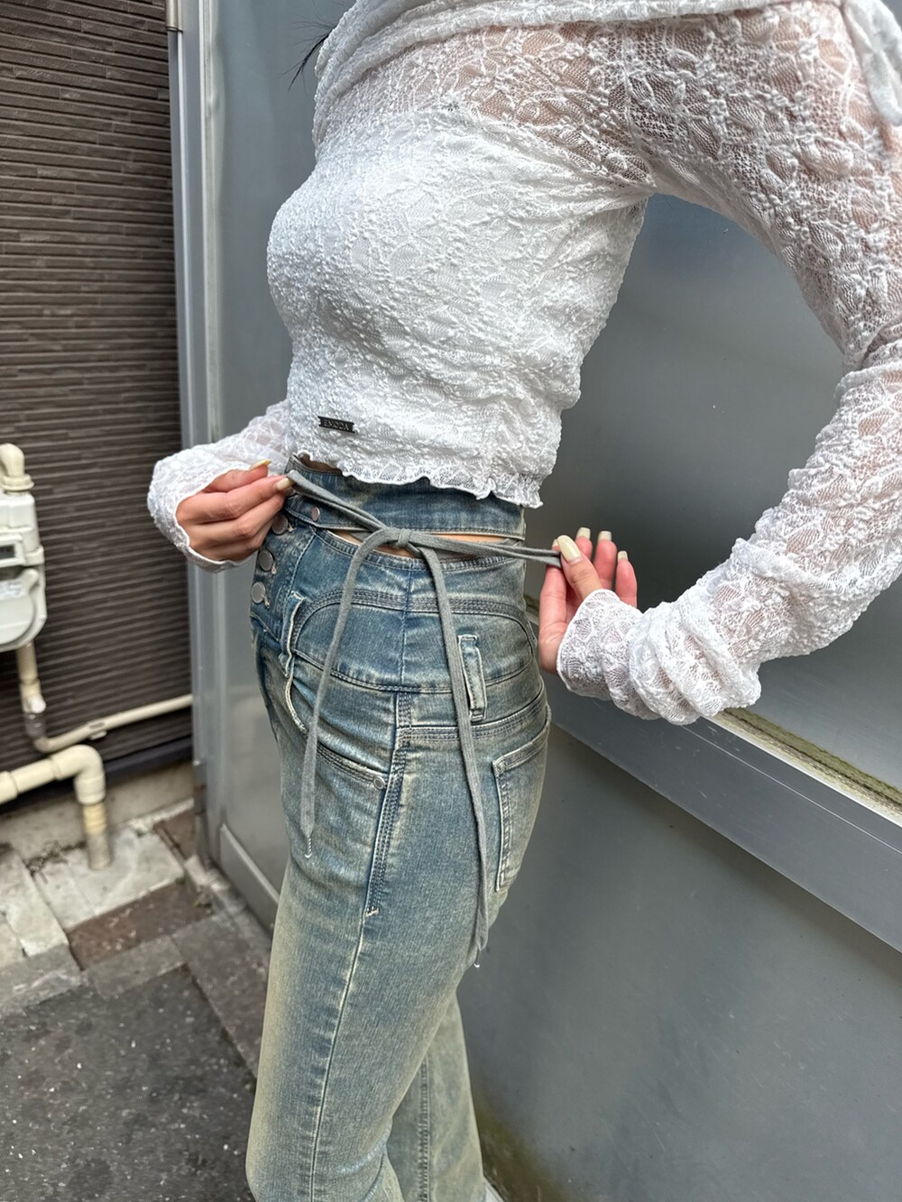 ブルー系のデニムパンツ、ブラック系のサンダル、ホワイト系のTシャツ/カットソーを着用したレディースの春コーディネートの3枚目の写真