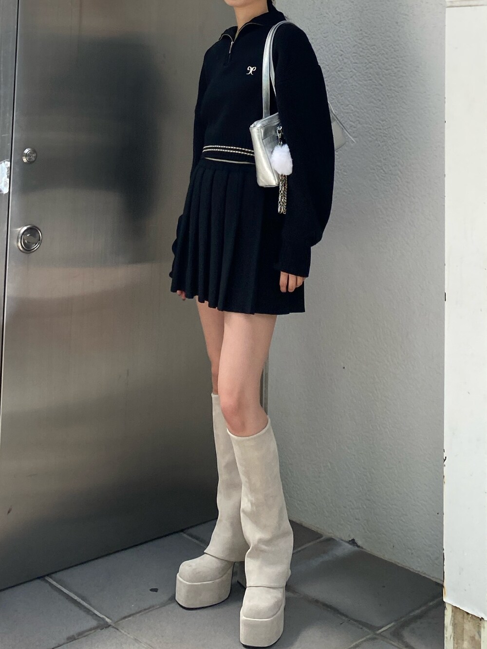 ホワイト系のブーツ、ブラック系のニット/セーター、ブラック系のスカートを着用したレディースの秋コーディネートの2枚目の写真