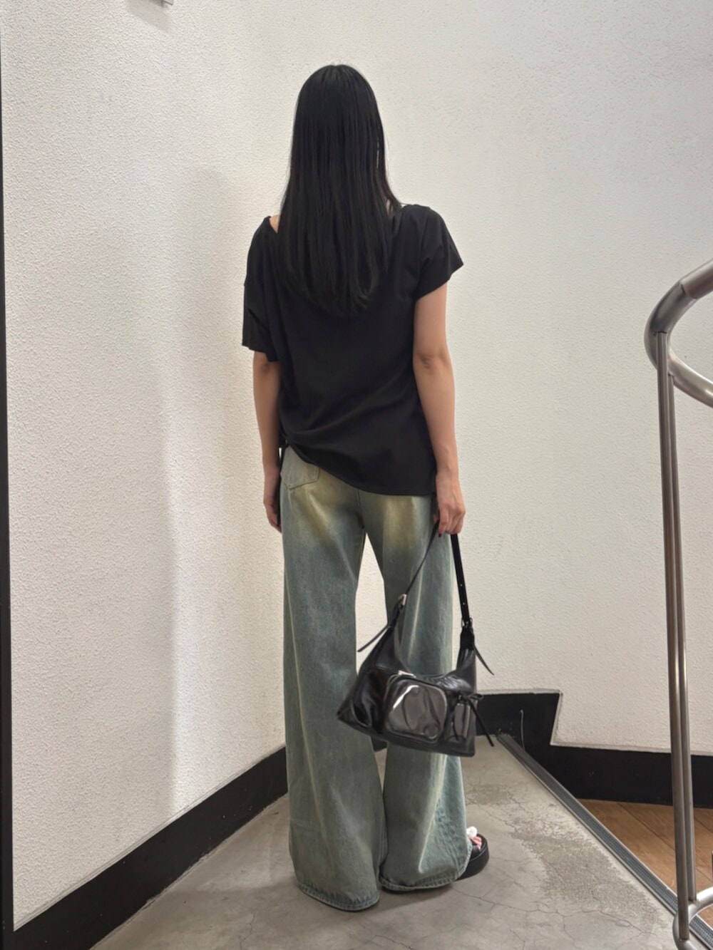 ブルー系のデニムパンツ、ブラック系のハンドバッグ、ブラック系のTシャツ/カットソーを着用したレディースの夏コーディネートの3枚目の写真