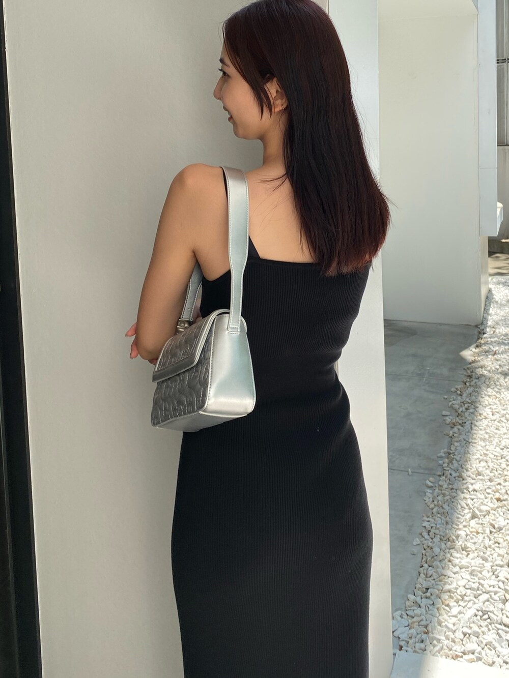 シルバー系のハンドバッグ、ブラック系のワンピースを着用したレディースの夏コーディネートの5枚目の写真