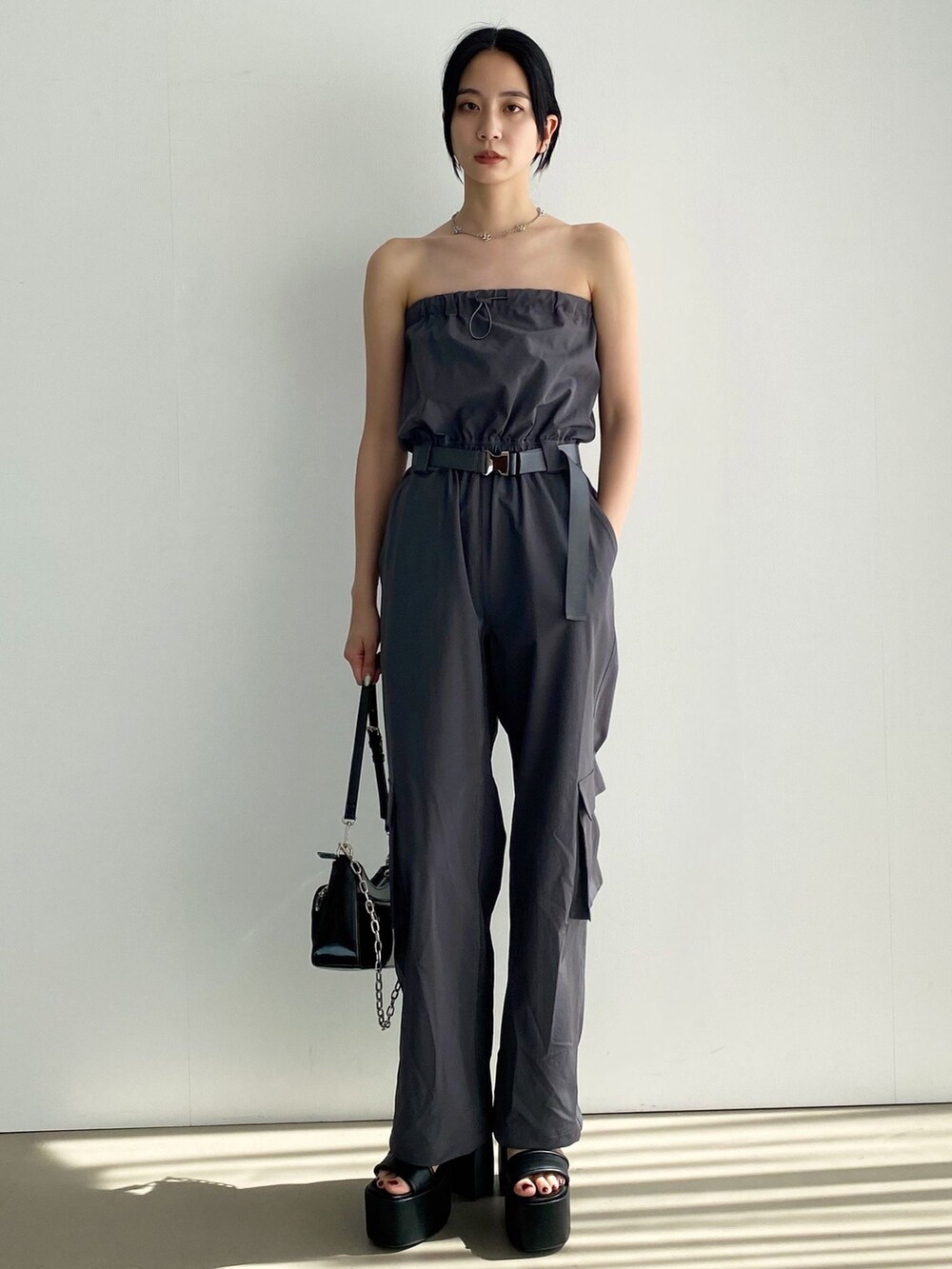 グレー系のつなぎ/オールインワン、ホワイト系のタンクトップ、ブラック系のハンドバッグを着用したレディースの夏コーディネートの2枚目の写真