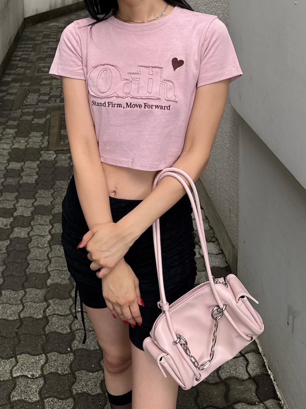 ピンク系のTシャツ/カットソー、ブラック系のスカート、ブラック系のサンダルを着用したレディースの夏コーディネートの2枚目の写真